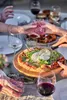 People enjoying a pizza outdoors at a table with wine. Produktbild-Vorschau