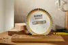 A circular saw blade with the DeWalt logo is placed on a wooden surface with wood shavings. Podgląd zdjęcia produktu