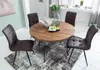 A round wooden dining table with four chairs in a dining room setting. Produktbild-Vorschau