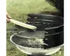 A hand is shown cleaning a grill grate with a wire brush. Anteprima dell’immagine prodotto