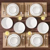 A top-down view of a table setting with multiple plates, bowls, cutlery, and glasses of water with lemon slices. Náhled obrázku produktu