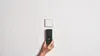 A hand holding a Bosch digital stud finder against a textured white wall, with a white square electrical outlet cover above it. Voir les images du produit