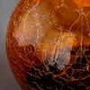 A close-up view of a cracked, amber-colored glass sphere. Produktbild-Vorschau
