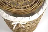 A close-up view of the top portion of a woven rattan laundry basket with a white fabric liner. Náhled obrázku produktu