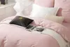 A close-up view of a pink satin duvet cover with decorative pillows and a book. Podgląd zdjęcia produktu