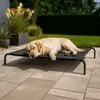 A dog is sleeping on an elevated outdoor dog bed on a patio. Náhled obrázku produktu