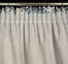 A close-up view of the top of a curtain, showing the pleats and the curtain rod with clips. Produktbild-Vorschau