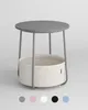A modern round side table with a fabric basket underneath, shown in a studio setting. Náhled obrázku produktu
