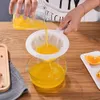 A person is pouring orange juice through a fine mesh strainer into a glass bowl. Produktbild-Vorschau