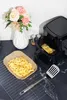 An air fryer with french fries, a baking paper liner, and a spatula on a kitchen counter, with a vase of flowers in the background. Anteprima dell’immagine prodotto