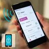 A hand holding a smartphone displaying a smart home app interface, with a smaller inset image of a smartphone with a smart home logo. Produktbild-Vorschau