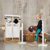 A young boy is playing with a hobby horse in front of a toy stable and a jump obstacle. Podgląd zdjęcia produktu