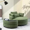 A green lounge chair and ottoman are shown in a room with a lamp and artwork. Produktbild-Vorschau