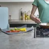 A person is cooking in a kitchen, with chopped vegetables on a cutting board. Náhľad obrázku produktu