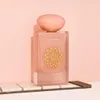 A perfume bottle with a pink hue and a gold decorative element on a white and pink background. Voir les images du produit