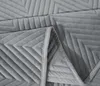 A close-up view of a gray quilted blanket with a chevron pattern. Podgląd zdjęcia produktu