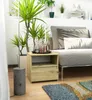 A bedside table with decorative items next to a sofa and a large plant. Produktbild-Vorschau
