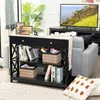 A console table with shelves and a drawer, placed in a living room setting next to a sofa and in front of a TV. Produktbild-Vorschau
