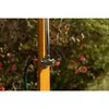 A close-up of an outdoor shower fixture attached to a wooden post, with a garden hose connected. Voir les images du produit