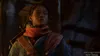A close-up of a young woman in a dimly lit, possibly medieval or fantasy setting. She is wearing a red scarf and a blue jacket. Produktbild-Vorschau