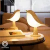 Two bird-shaped lamps on a marble table next to a book. Voir les images du produit