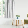 A white curtain hangs next to a window, with a small white table and a green chair in the foreground. Produktbild-Vorschau