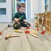 A young boy is playing with a wooden toy tool set on the floor. Anteprima dell’immagine prodotto