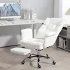 A white ergonomic office chair with a footrest is shown in a home office setting. Podgląd zdjęcia produktu