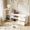 A white shoe cabinet with a cushioned bench, drawers, and a cabinet with doors, placed in a room with artwork on the wall and a rug on the floor. Produktbild-Vorschau
