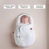 A baby wrapped in a white swaddle, with text boxes describing features above. Anteprima dell’immagine prodotto