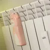A pink ceramic pig-shaped humidifier hangs on a white radiator. Produktbild-Vorschau