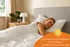 A woman sleeping peacefully in a bed under a white duvet. Produktbild-Vorschau