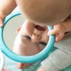 A baby looking into a mirror held by their hands. Produktbild-Vorschau