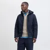 A man wearing a navy jacket and beige sweater, posing against a white background. Produktbild-Vorschau
