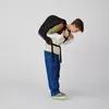 A young person wearing a backpack and adjusting the straps. Produktbild-Vorschau