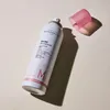 A white spray can with a pink cap is placed on a light beige surface, casting a shadow. Produktbild-Vorschau