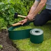 A person is installing green garden edging in a grassy area next to a garden bed. Produktbild-Vorschau
