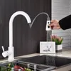 A white kitchen faucet with a pull-out spray is shown in use over a sink, with a small framed picture and a potted plant in the background. Náhľad obrázku produktu