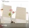 Two cream-colored dining chairs are shown at a table with flowers in a vase. Produktbild-Vorschau