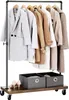 A clothes rack with multiple coats and two storage bins underneath, placed on a wooden base with wheels. Náhled obrázku produktu
