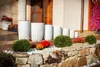 A row of white planters of varying sizes are displayed on a stone wall in front of a building. Anteprima dell’immagine prodotto