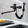 A black kitchen faucet with a pull-out sprayer is mounted on a tiled wall above a sink. Produktbild-Vorschau