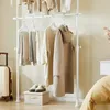 A white telescoping clothes rack with various garments hanging on it, a suitcase, and a storage box with shoes on top. Náhľad obrázku produktu