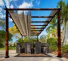An outdoor dining area under a wooden pergola with a retractable canopy, featuring a table and chairs. Podgląd zdjęcia produktu
