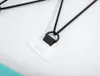 A close-up view of a black D-ring attached to a white patch with black stitching, connected to black elastic cords. Produktbild-Vorschau