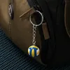 A close-up of a keychain with a miniature volleyball attached to a zipper pull of a bag. Produktbild-Vorschau