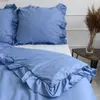 A close-up view of a blue bedding set with ruffles on a bed. Produktbild-Vorschau