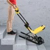 A person is using a yellow and black manual stair chair on a concrete staircase. Podgląd zdjęcia produktu