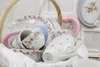 A collection of floral-patterned tableware, including plates, bowls, and mugs, arranged in a wicker basket. Produktbild-Vorschau
