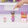A child's hand points to a toy art studio set with two figurines on a white shelf. Produktbild-Vorschau